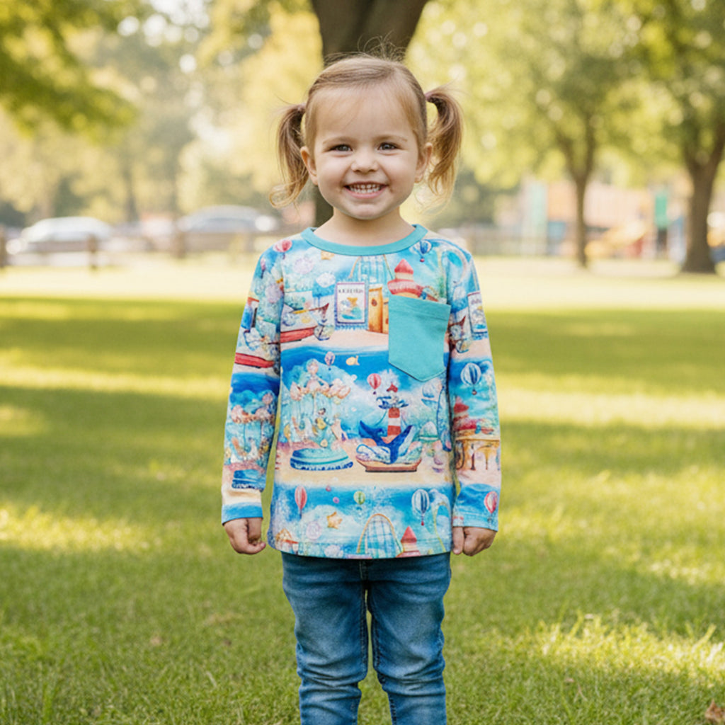 Girl wearing a colorful long-sleeve bamboo tee shirt with n underwater carnival design in a park