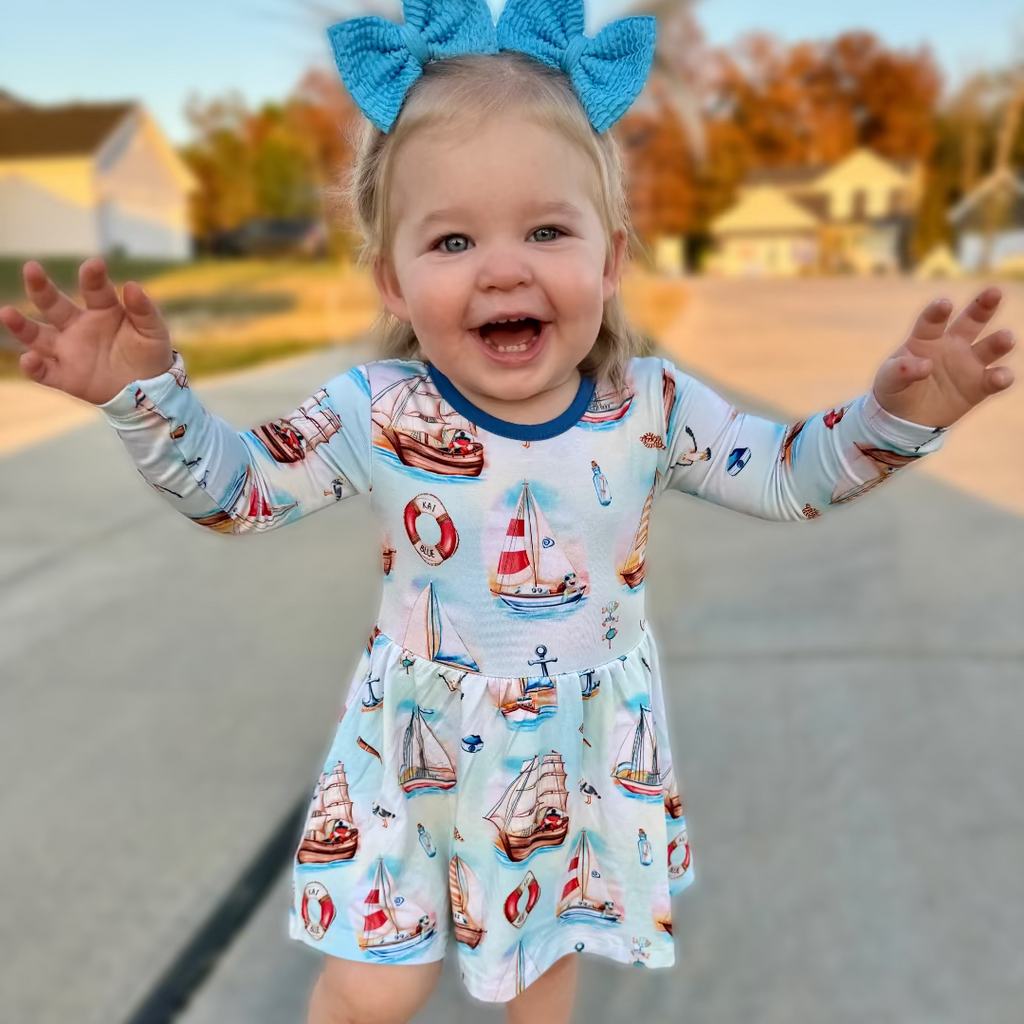 Child wearing a Kai Blue Bodysuit Twirl Dress with sailboat pattern