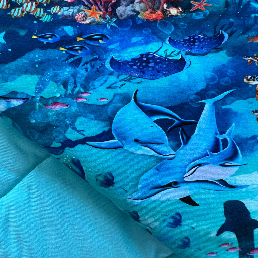 Folded quilted bamboo blanket close-up view with underwater ocean theme by Kai Blue